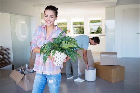 people moving boxes - Portrait of smiling woman holding potted plant in new house Stock Photo - Premium Royalty-Free, Code: 6113-07147244