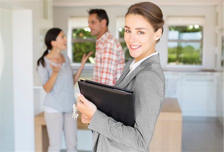 real estate - Portrait of smiling realtor with couple in background Foto de stock - Sin royalties Premium, Código: 6113-07147253