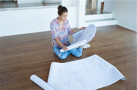remodeling - Woman examining blueprints on floor in empty living room Stock Photo - Premium Royalty-Free, Code: 6113-07147201