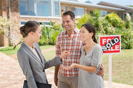 ethnic holding sign - Realtor giving couple keys to new house Stock Photo - Premium Royalty-Free, Code: 6113-07147217
