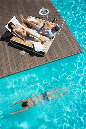 simsearch:6113-07147433,k - Couple relaxing on lounge chairs at poolside Stock Photo - Premium Royalty-Free, Code: 6113-07147390