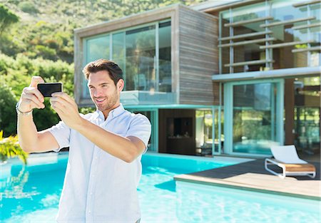 simsearch:6113-07147497,k - Man taking self-portrait with camera phone at poolside Stock Photo - Premium Royalty-Free, Code: 6113-07147473