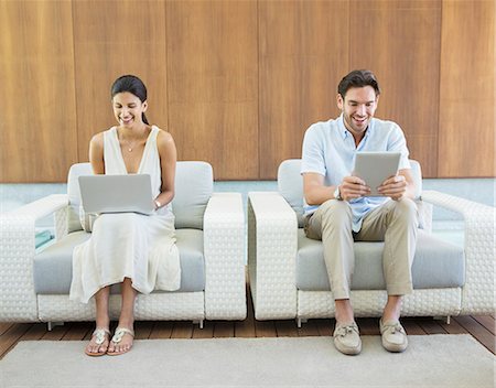 Couple using laptop and digital tablet in armchairs Foto de stock - Royalty Free Premium, Número: 6113-07147476