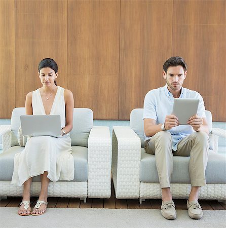 Couple using digital tablet and laptop in armchairs Stock Photo - Premium Royalty-Free, Code: 6113-07147487