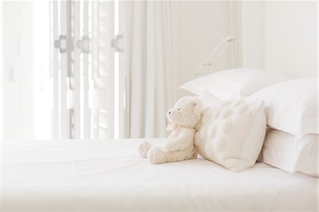 Teddy bear and pillows on white bed Photographie de stock - Premium Libres de Droits, Code: 6113-07147501