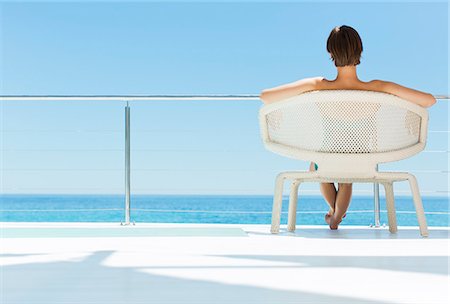 Woman in chair looking at ocean view Stock Photo - Premium Royalty-Free, Code: 6113-07147530