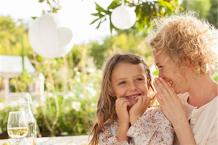 sharing a drink - Mother and daughter whispering outdoors Stock Photo - Premium Royalty-Free, Code: 6113-07147663