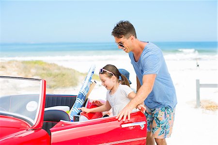 Father helping daughter into convertible on beach Stock Photo - Premium Royalty-Free, Code: 6113-07147699