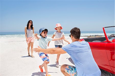 Father reaching to hug children on beach next to convertible Stock Photo - Premium Royalty-Free, Code: 6113-07147746