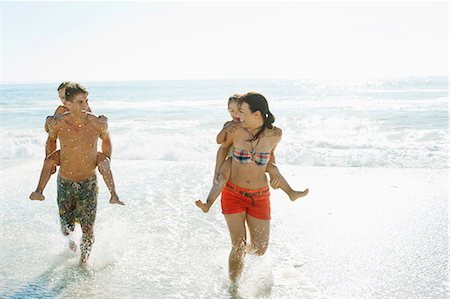 running kids - Parents carrying daughters piggyback in surf at beach Stock Photo - Premium Royalty-Free, Code: 6113-07147728