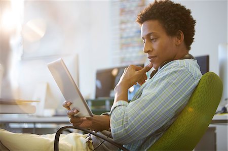 side view of someone sitting in chair - Businessman using digital tablet in office Stock Photo - Premium Royalty-Free, Code: 6113-07147856