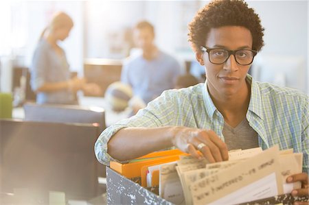 portrait of smiling casual businessman with paperwork in office - Businessman sorting through files in office Photographie de stock - Premium Libres de Droits, Code: 6113-07147894