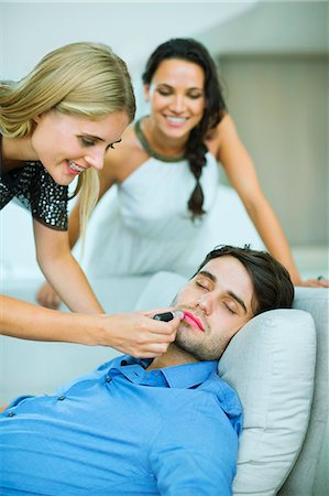 Woman applying lipstick to sleeping man Foto de stock - Royalty Free Premium, Número: 6113-07148079