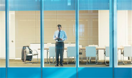 full body man standing alone holding tablet - Businessman standing in conference room Stock Photo - Premium Royalty-Free, Code: 6113-07158908