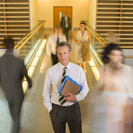 simsearch:6113-07242758,k - Businessman standing in busy office corridor Stock Photo - Premium Royalty-Free, Code: 6113-07159047