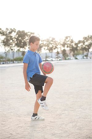 Boy kneeing soccer ball in sand Foto de stock - Sin royalties Premium, Código: 6113-07159157