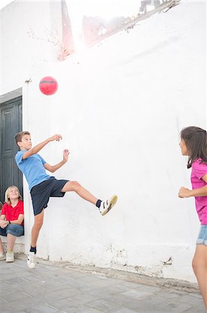 Children playing with soccer ball in alley Stock Photo - Premium Royalty-Free, Code: 6113-07159159
