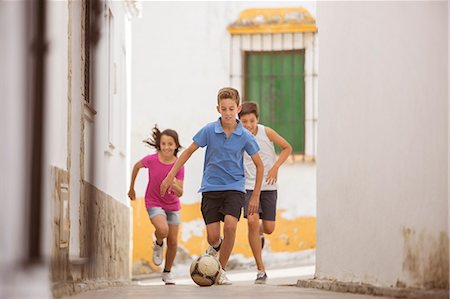 running teenage boy & girl - Children playing with soccer ball in alley Stock Photo - Premium Royalty-Free, Code: 6113-07159172