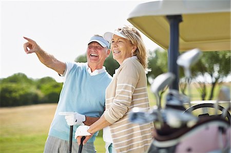 sunshine and looking away and togetherness - Senior couple standing next to golf cart Foto de stock - Sin royalties Premium, Código: 6113-07159238