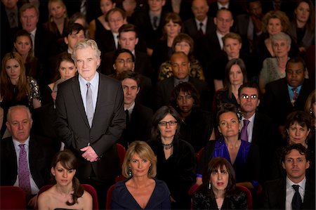 standing out from the crowd - Serious man standing in theater audience Stock Photo - Premium Royalty-Free, Code: 6113-07159364