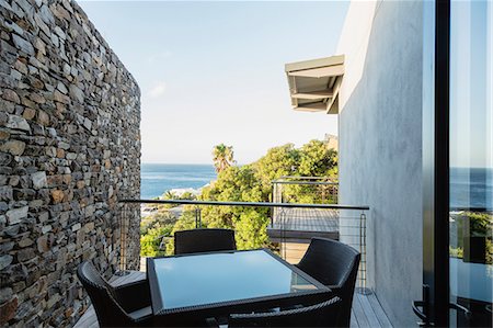 Table and chairs on luxury balcony overlooking ocean Foto de stock - Sin royalties Premium, Código: 6113-07159473