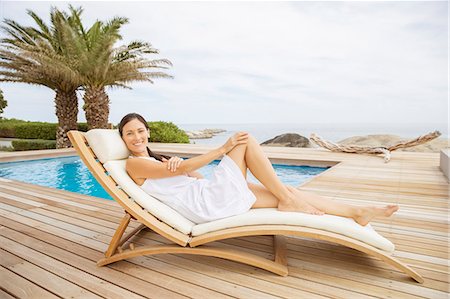 portraits and one person and smiling not black not kids not babies not teens not illustration - Woman relaxing in lounge chair at poolside Stock Photo - Premium Royalty-Free, Code: 6113-07159499