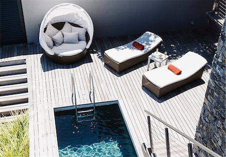 simsearch:6113-07159818,k - Lounge chairs on wooden deck by modern pool Foto de stock - Royalty Free Premium, Número: 6113-07159428