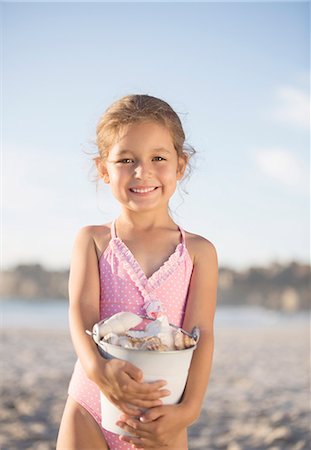 Girl holding bucket of shells on beach Photographie de stock - Premium Libres de Droits, Code: 6113-07159570