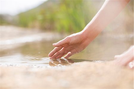 Woman dipping fingers in rural pond Stock Photo - Premium Royalty-Free, Code: 6113-07159675