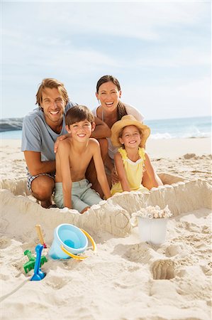 siblings at beach - Family sitting in sandcastle on beach Stock Photo - Premium Royalty-Free, Code: 6113-07159605