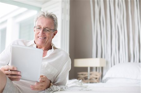 senior with computer - Older man using digital tablet on bed Foto de stock - Sin royalties Premium, Código: 6113-07159619