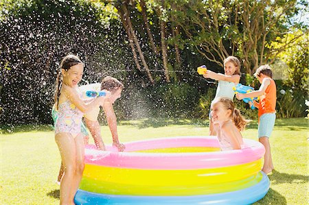 family fun outdoors summer grass - Father and children playing with water guns in backyard Stock Photo - Premium Royalty-Free, Code: 6113-07159702