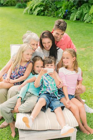 Family using cell phone together in backyard Foto de stock - Sin royalties Premium, Código: 6113-07159706