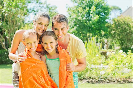 portrait of a daughter hugging her father - Parents wrapping daughters in towels in backyard Foto de stock - Sin royalties Premium, Código: 6113-07159715