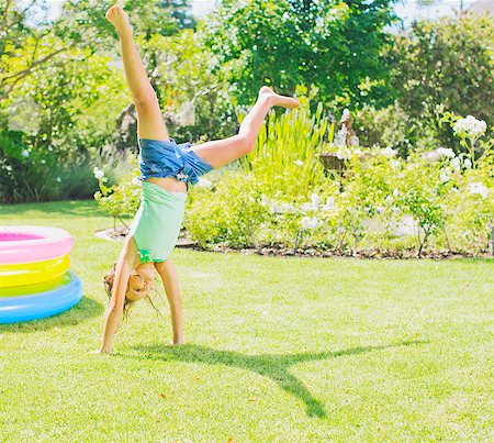 single kid playing - Girl doing cartwheels in backyard Stock Photo - Premium Royalty-Free, Code: 6113-07159720