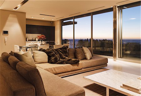 Modern living room overlooking ocean at sunset Foto de stock - Sin royalties Premium, Código: 6113-07159862