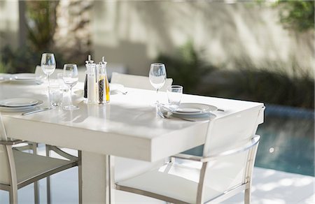 simsearch:6113-07160199,k - Set dining table on modern patio at poolside Foto de stock - Sin royalties Premium, Código: 6113-07159868