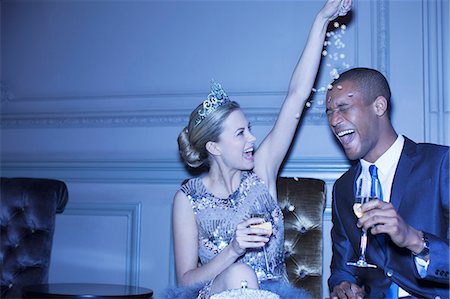 party in lounge - Woman in tiara sprinkling confetti over man Stock Photo - Premium Royalty-Free, Code: 6113-07159903