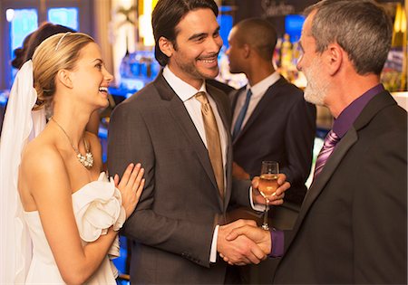 Man shaking hands with groom at wedding reception Stock Photo - Premium Royalty-Free, Code: 6113-07159902