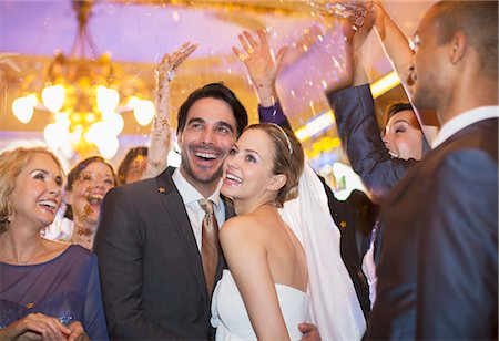 Friends throwing confetti over bride and groom at wedding reception Stock Photo - Premium Royalty-Free, Code: 6113-07160040