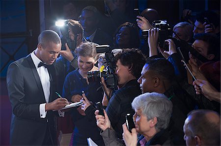 simsearch:693-06324878,k - Well dressed male celebrity signing autographs at red carpet event Photographie de stock - Premium Libres de Droits, Code: 6113-07160058