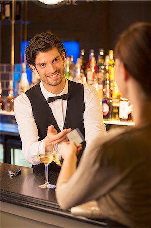 Well dressed bartender taking credit card from customer in luxury bar Stock Photo - Premium Royalty-Free, Code: 6113-07160012