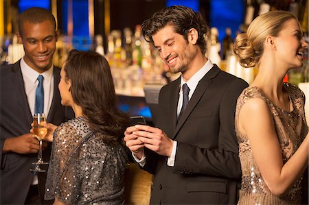 robes de soirée - Well dressed man looking down at cell phone and smiling in luxury bar Photographie de stock - Premium Libres de Droits, Code: 6113-07160020