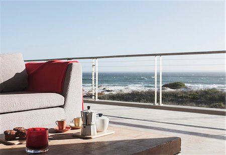 Breakfast on coffee table on modern patio overlooking ocean Photographie de stock - Premium Libres de Droits, Code: 6113-07160150