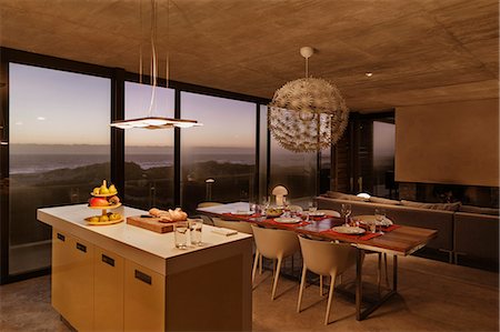 simsearch:6113-07589653,k - Breakfast bar and dining table in modern kitchen overlooking ocean at dusk Fotografie stock - Premium Royalty-Free, Codice: 6113-07160158