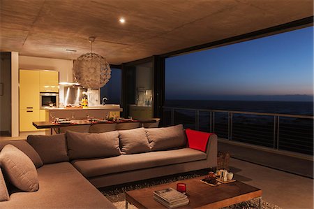 simsearch:6113-07160187,k - Sofa and dining table in modern living room overlooking ocean Photographie de stock - Premium Libres de Droits, Code: 6113-07160175