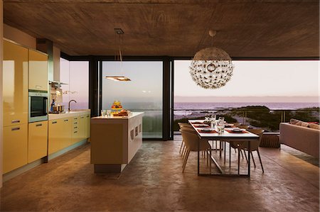 Modern kitchen and dining room overlooking ocean at sunset Stock Photo - Premium Royalty-Free, Code: 6113-07160138