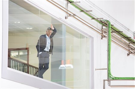 Supervisor leaning on glass window in warehouse Stock Photo - Premium Royalty-Free, Code: 6113-07160246