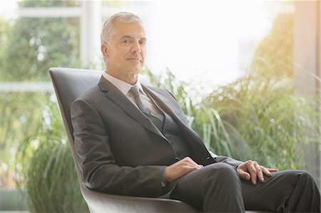 side view of someone sitting in chair - Businessman sitting in leather chair Stock Photo - Premium Royalty-Free, Code: 6113-07160412