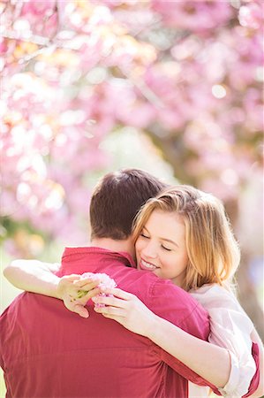 simsearch:6113-07160576,k - Couple hugging under tree with pink blossoms Stock Photo - Premium Royalty-Free, Code: 6113-07160594